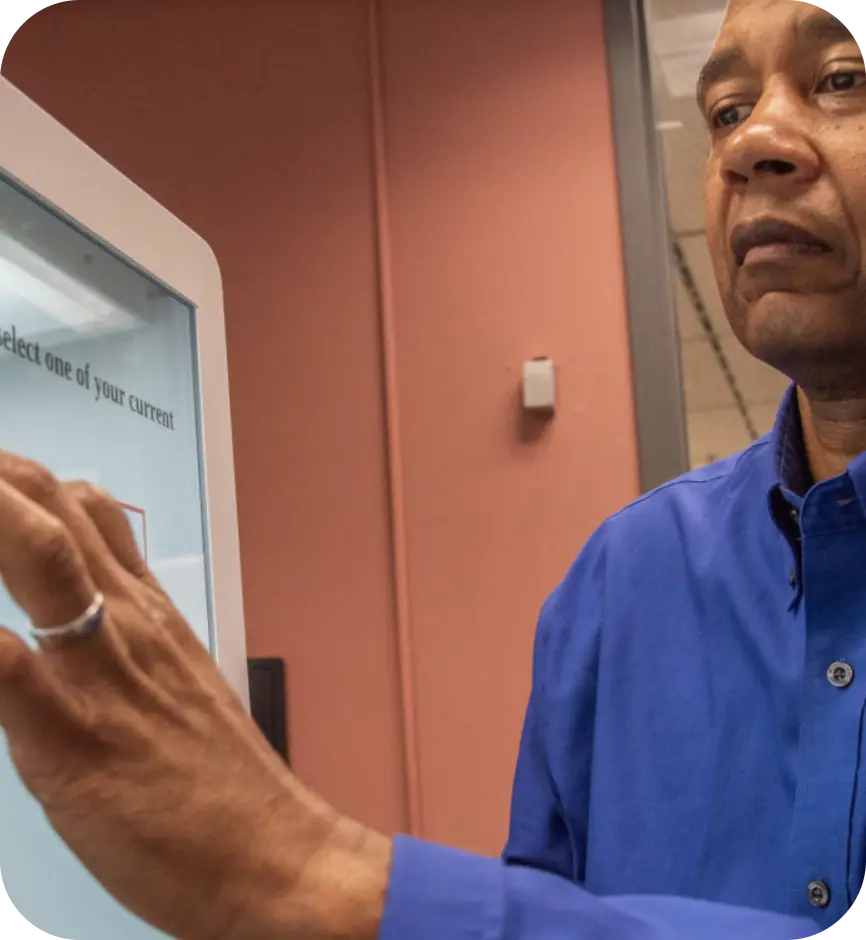 A man in a blue shirt has his hand pressed against the screen of a voting machine